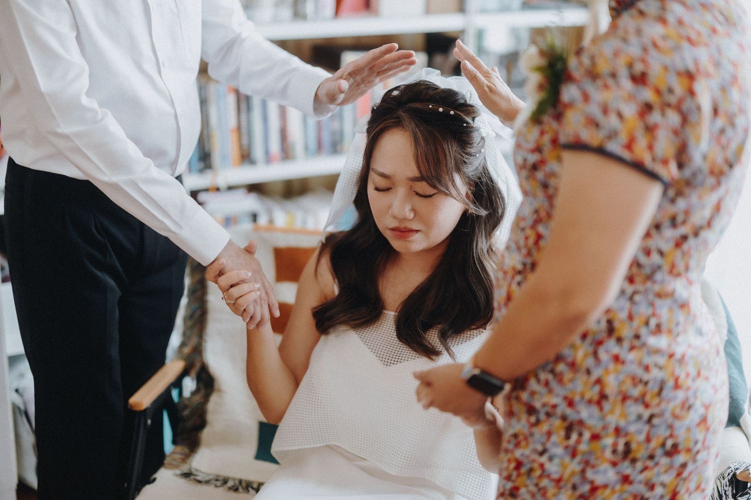 A touching moment during wedding preparations as attendants help with final touches.