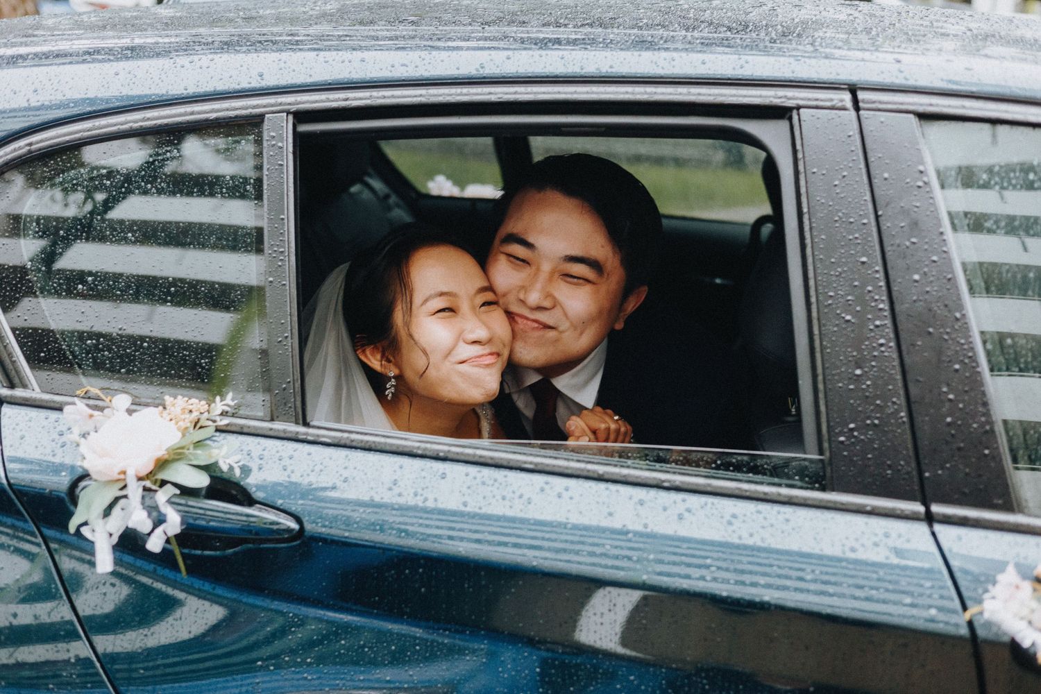 Two people share a happy moment while sitting in a car decorated with white ribbons.