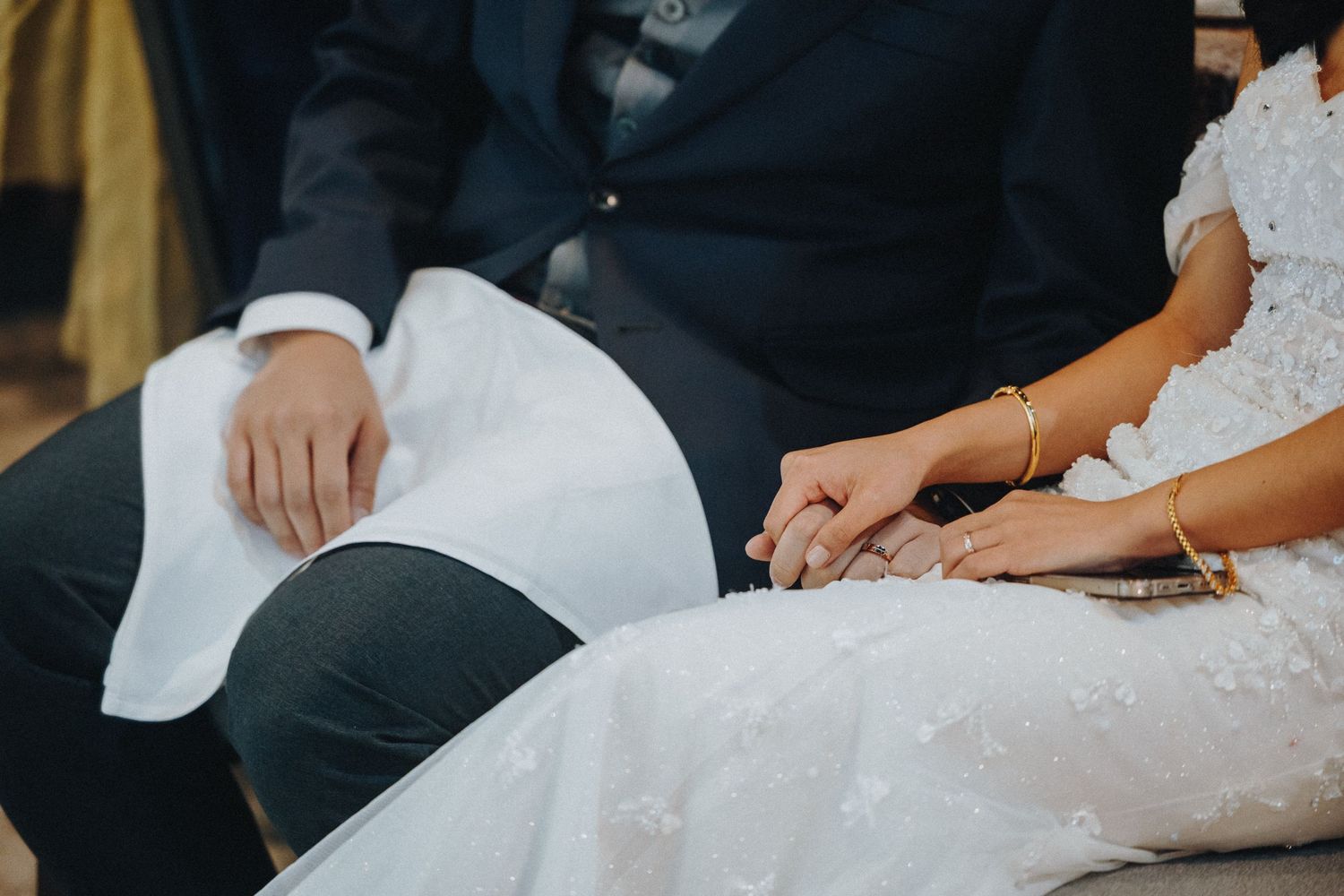 Close-up detail shot of wedding attire showing white dress fabric against dark suit.