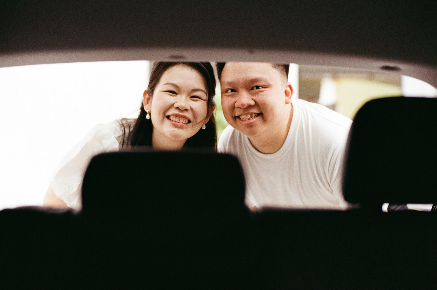 A joyful couple smiling through a car window on a casual outing together.