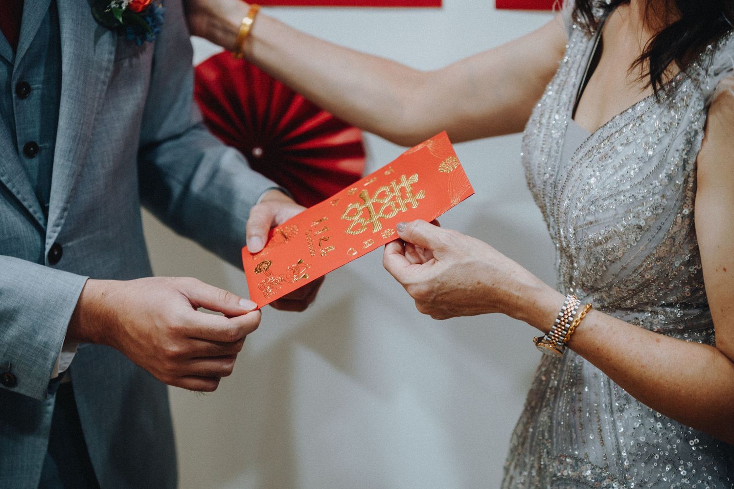 Couple exchanging red envelopes during a traditional wedding ceremony.
