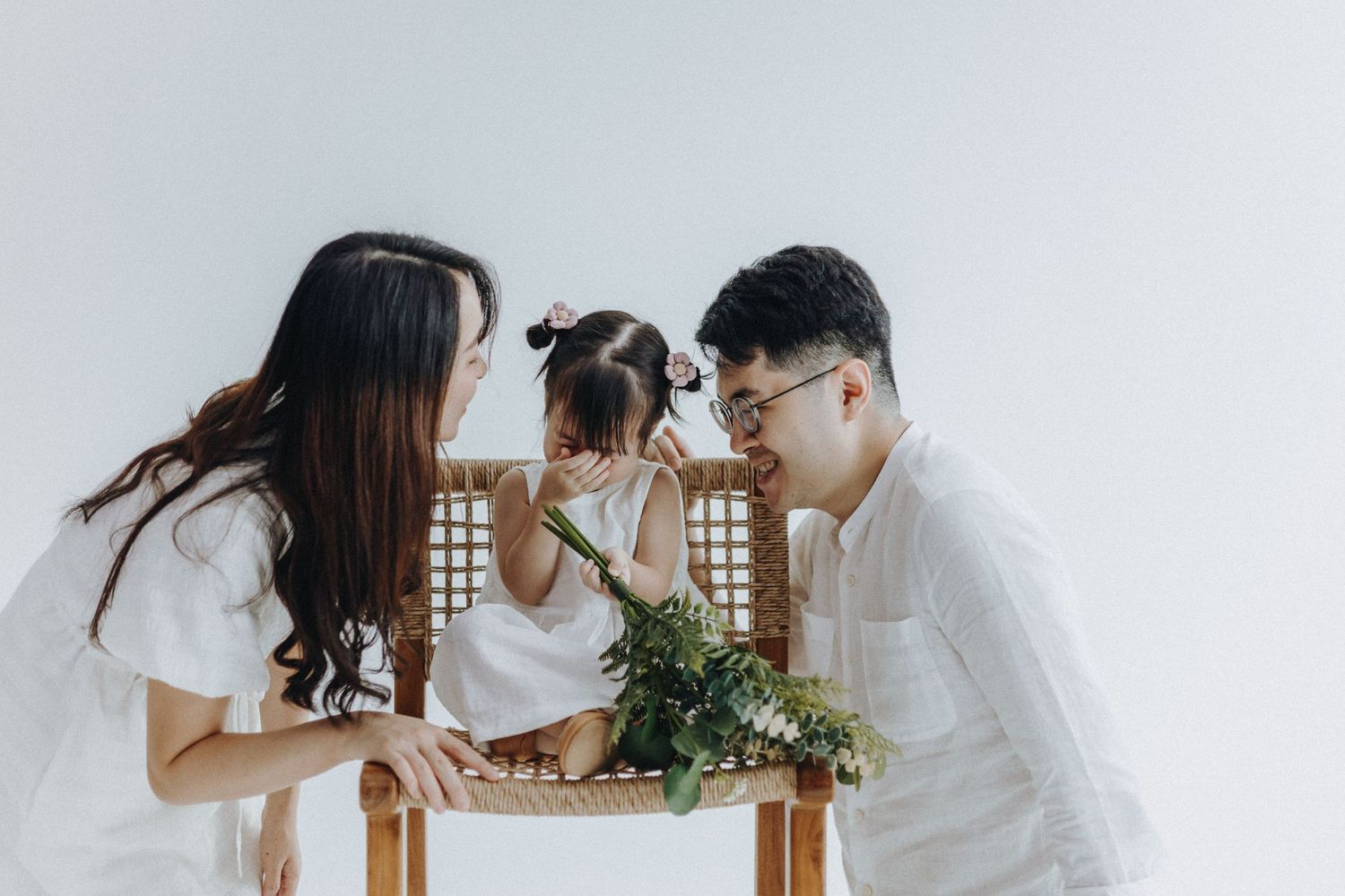 Family in white clothing shares tender moment at home during casual lifestyle photo session.