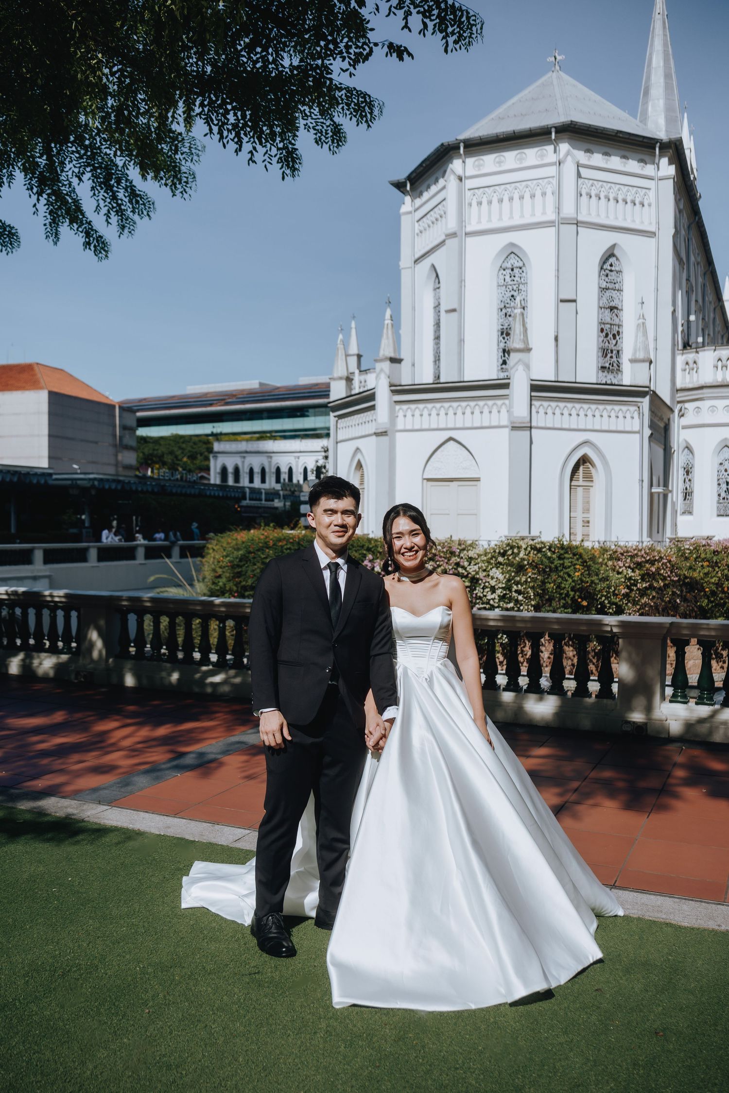 Bride and groom holding hands in front of a white Gothic church on their wedding day.