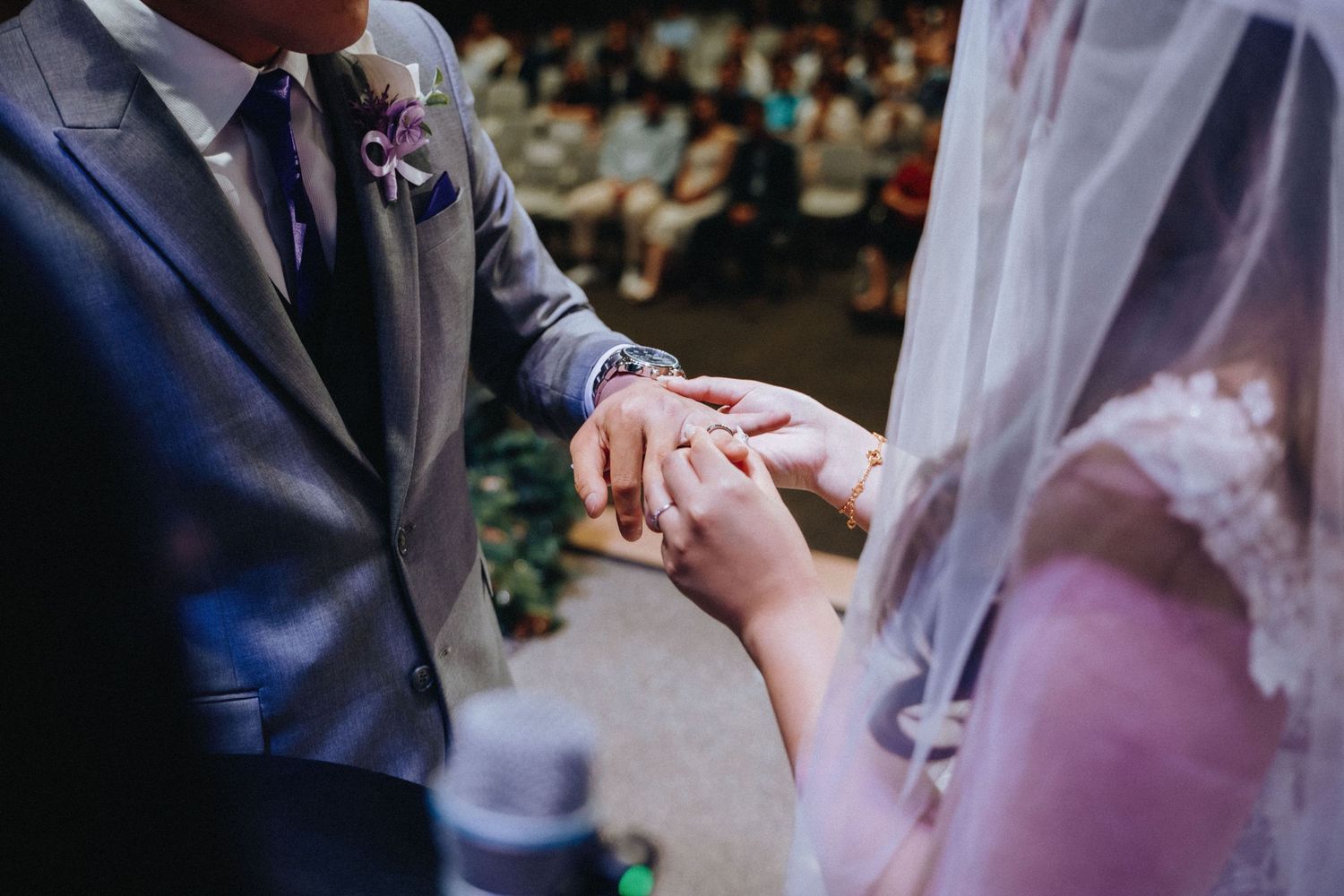 Close-up view of hands exchanging wedding rings during an intimate ceremony.