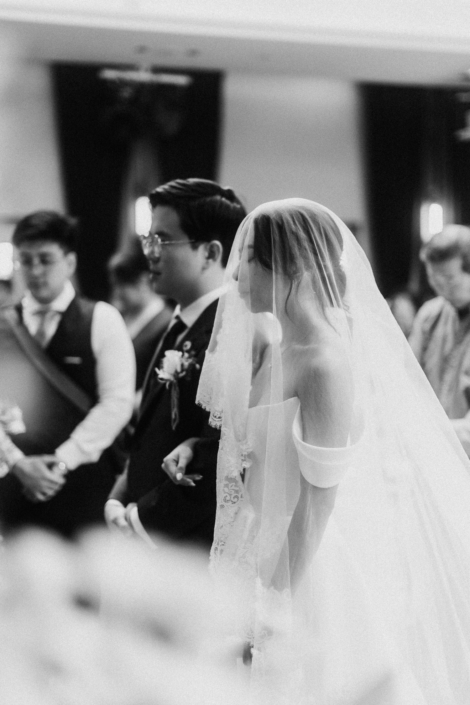 Black and white photo of a wedding ceremony with couple and guests inside a church.