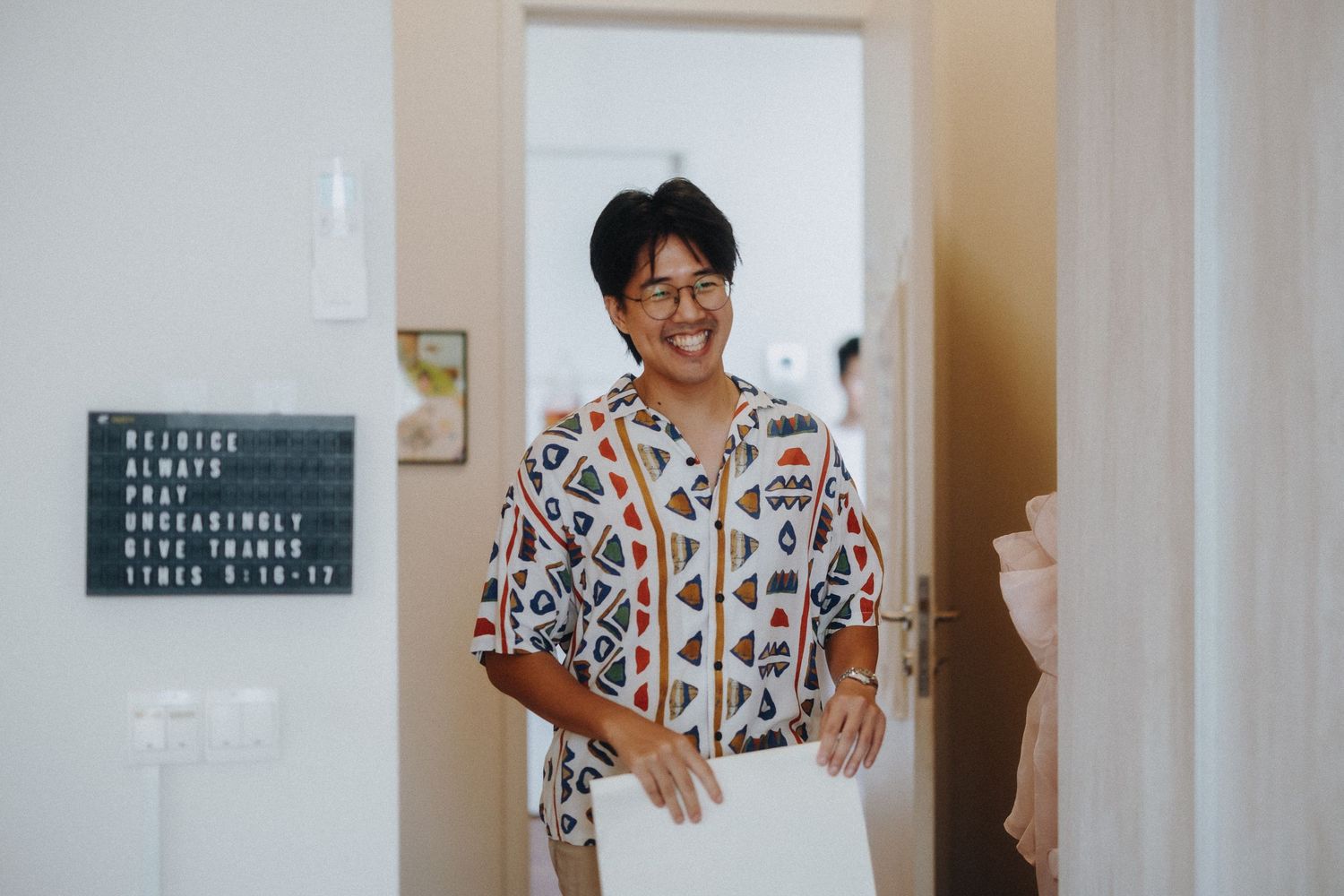 A guest in a patterned shirt smiling while standing in a doorway.
