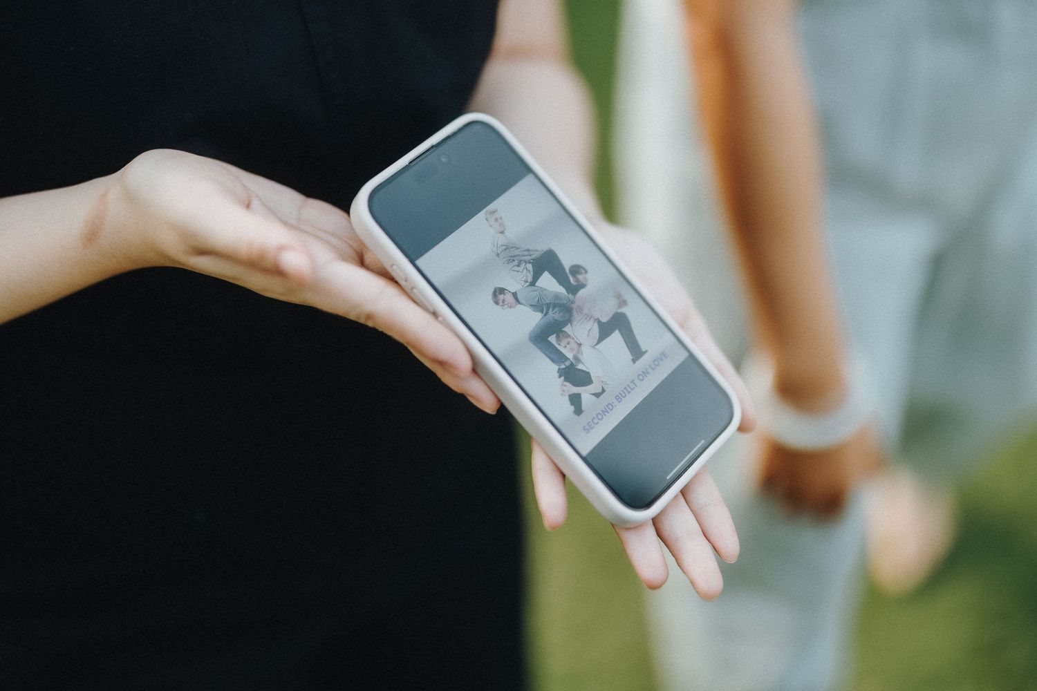 A hand holds up a smartphone displaying a black and white photograph.