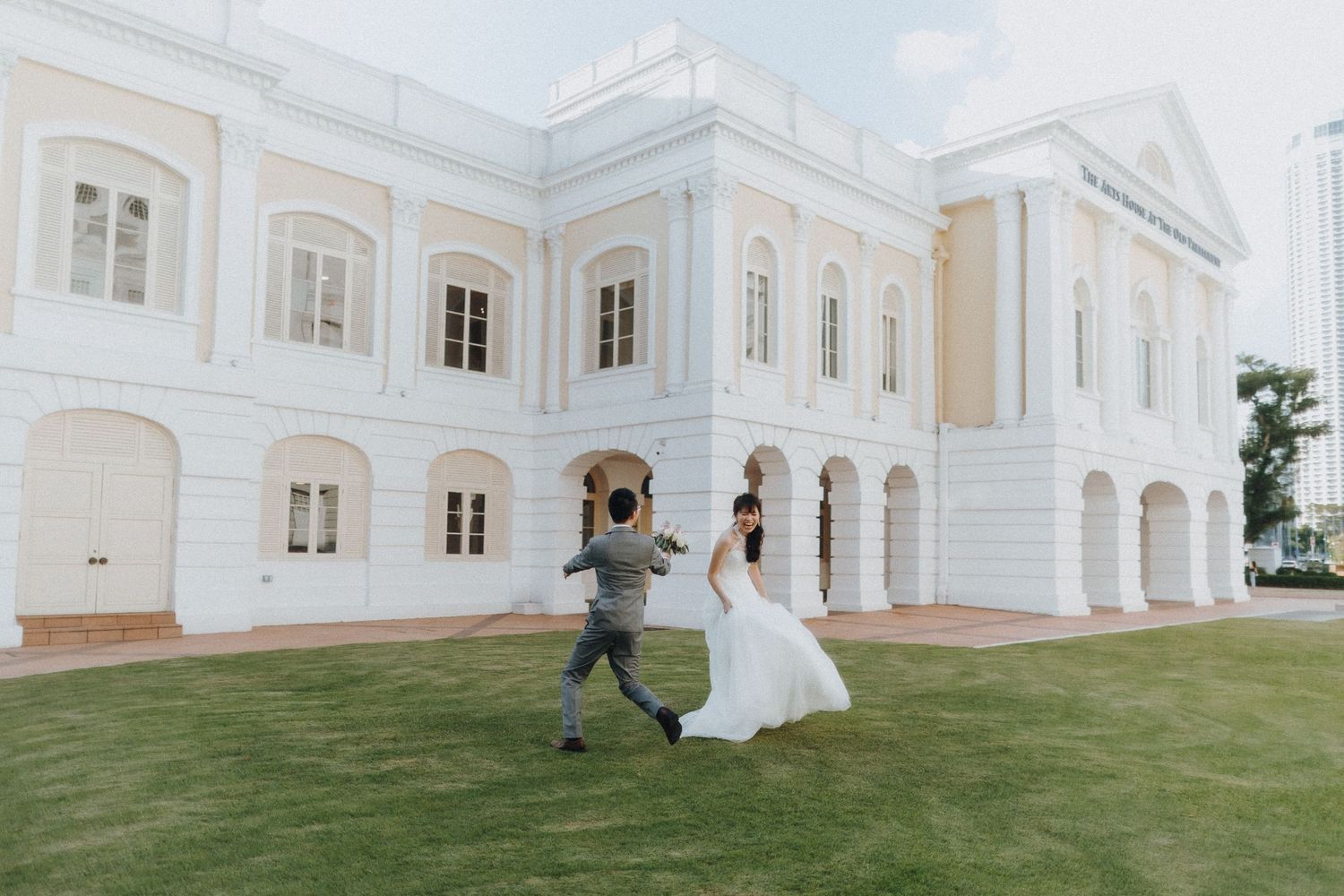 Wedding photography session outside a grand white colonial-style building with manicured lawn.