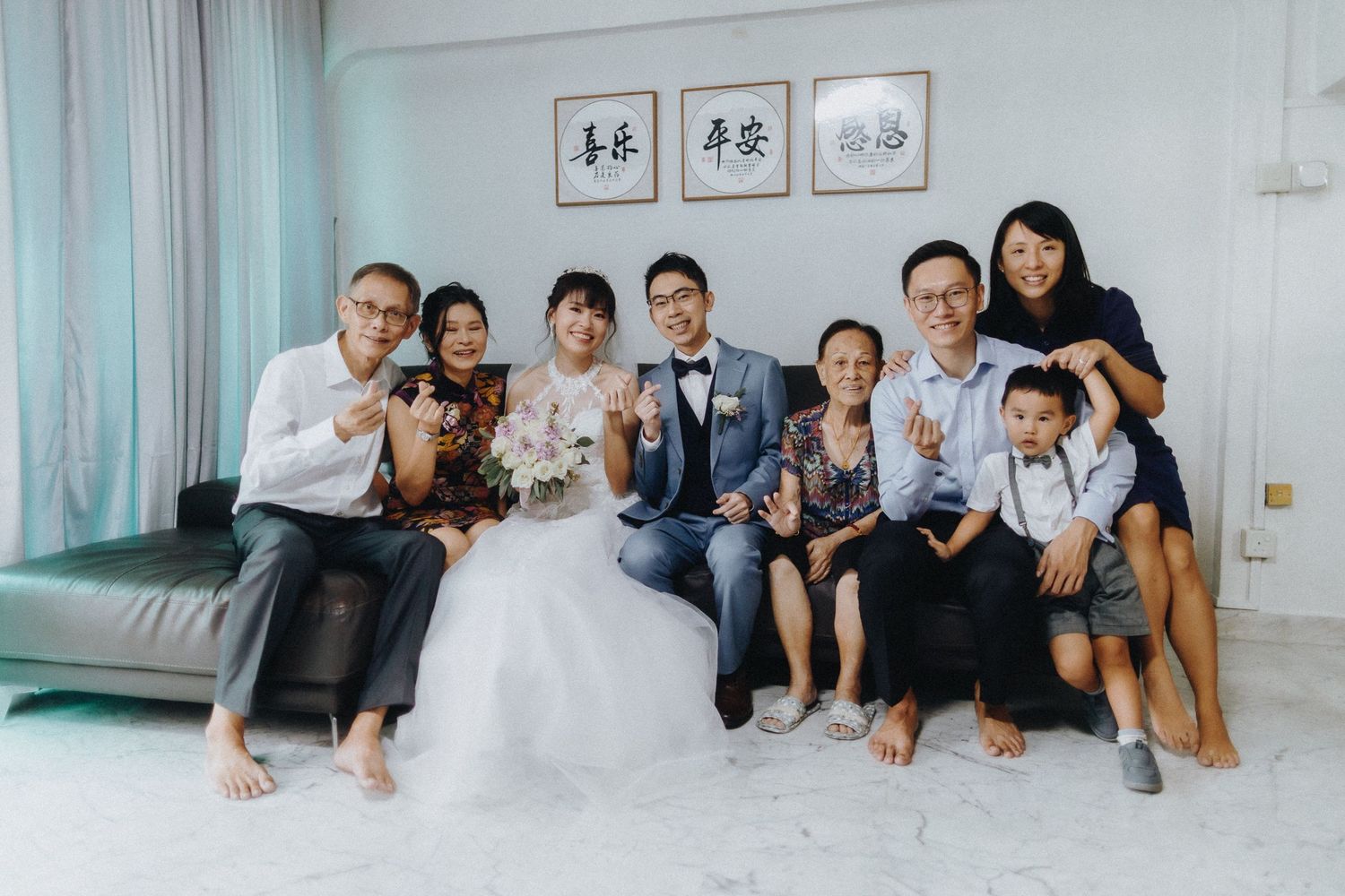 A wedding celebration with extended family posing casually together on a couch with framed artwork visible.