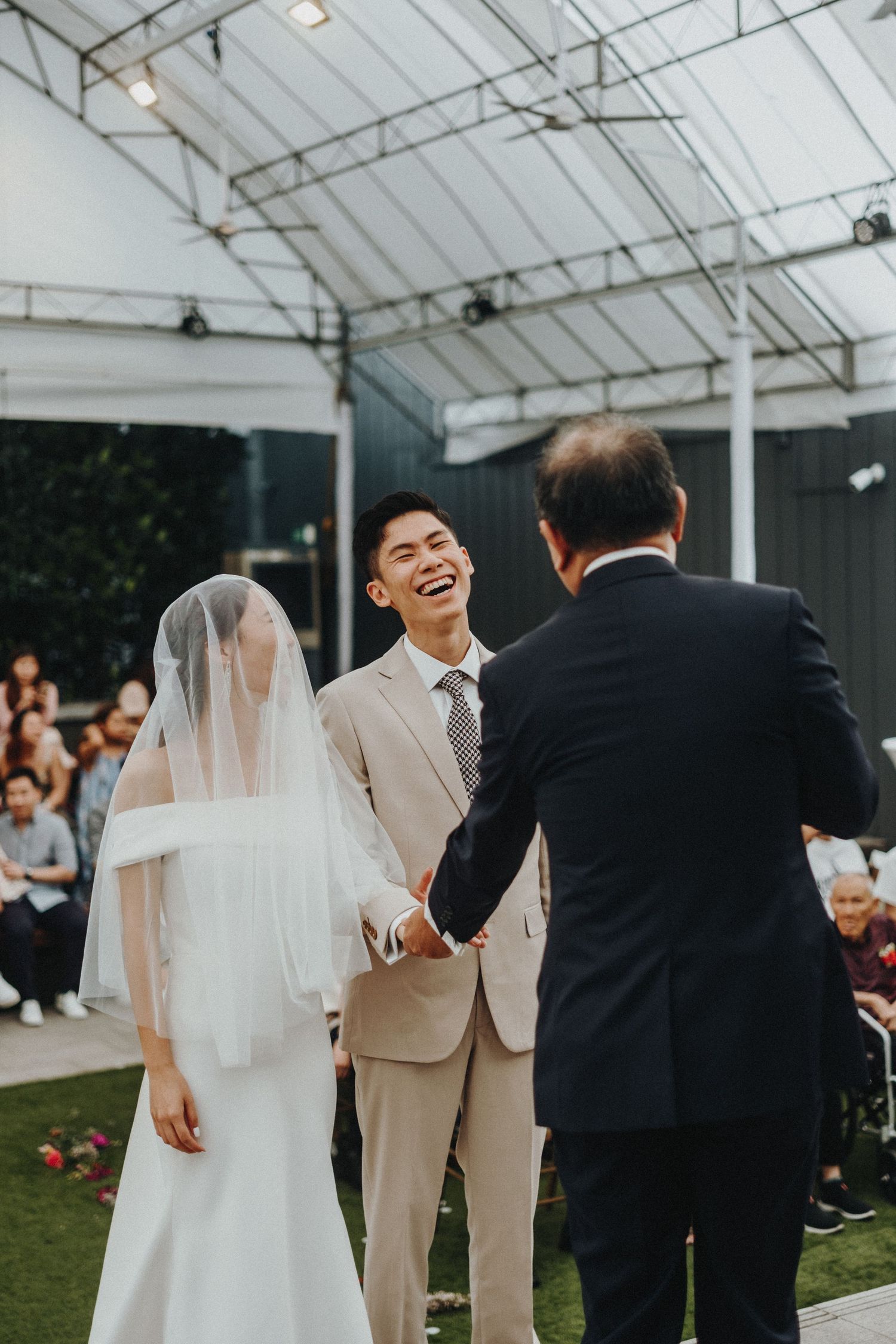 Joyful celebration under a white tent during an outdoor wedding ceremony.
