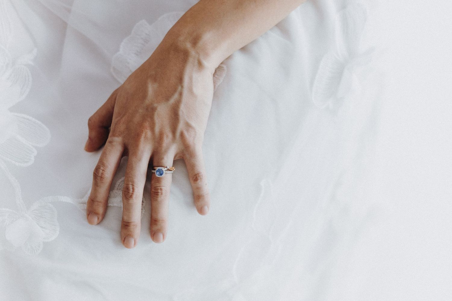 Close-up shot of hands with wedding rings against white background.