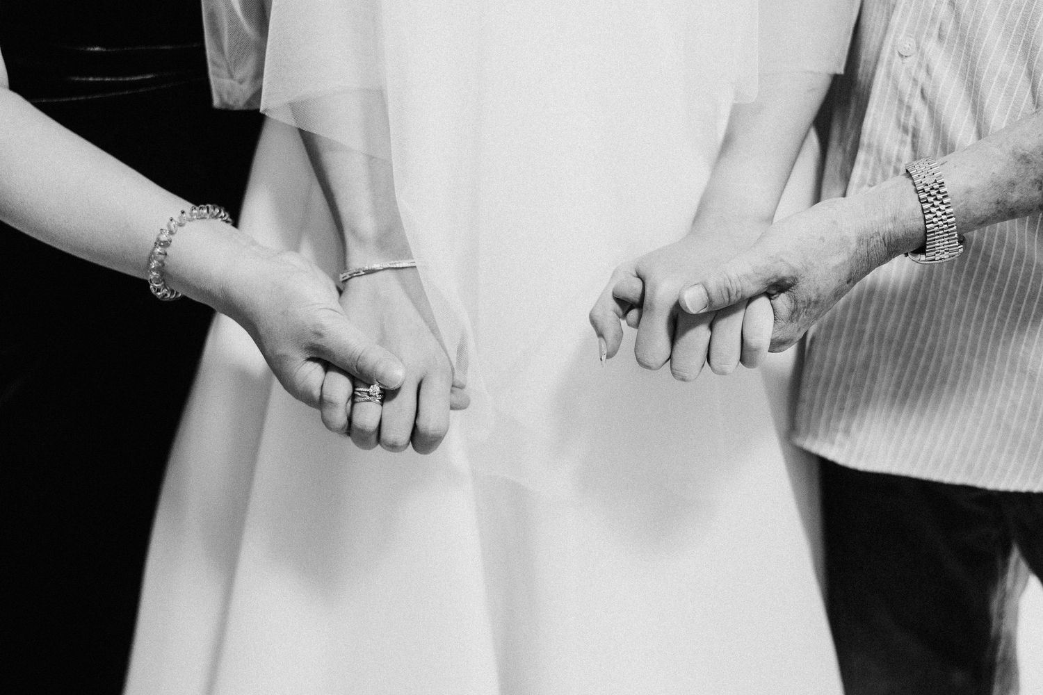 Black and white close-up photos of hands with wedding rings showing tender moments of a newly married couple.