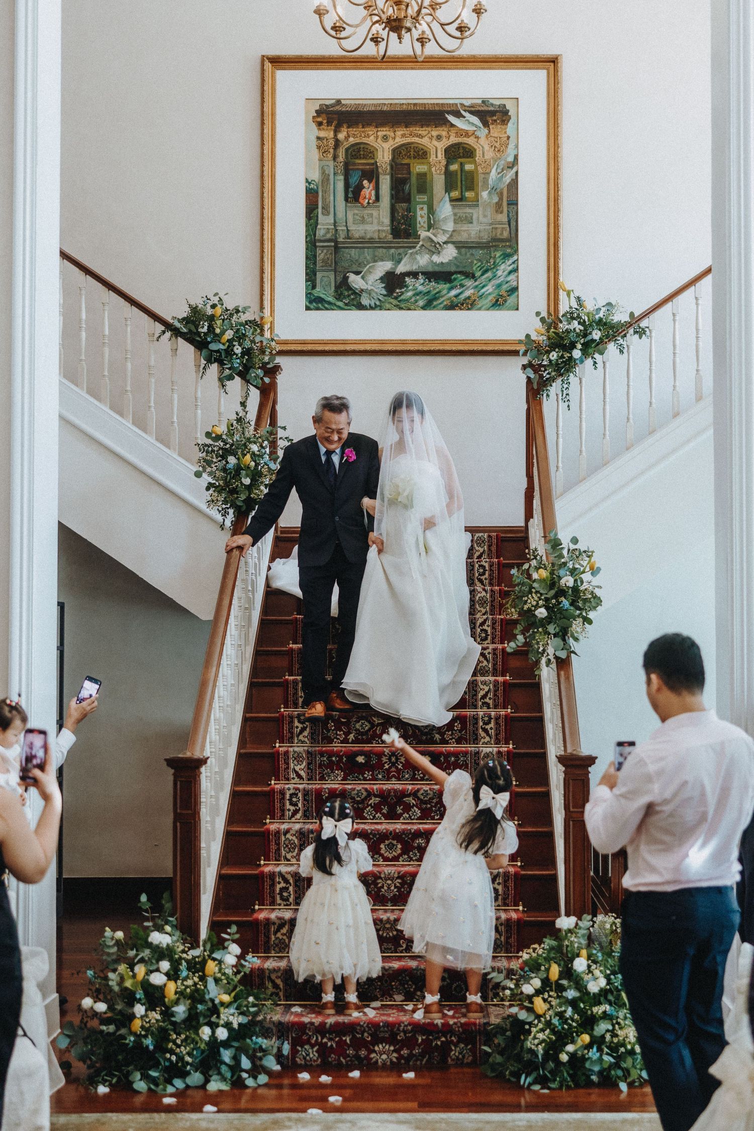 Grand staircase decorated with floral arrangements and greenery for an elegant indoor wedding ceremony.