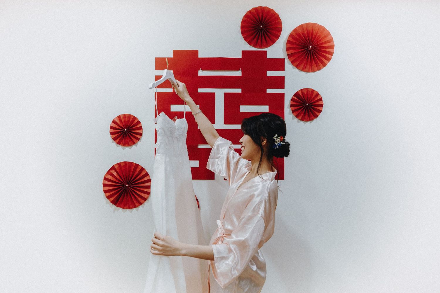 Woman in white dress holds modern red paper decorations against white background in sequential photos.