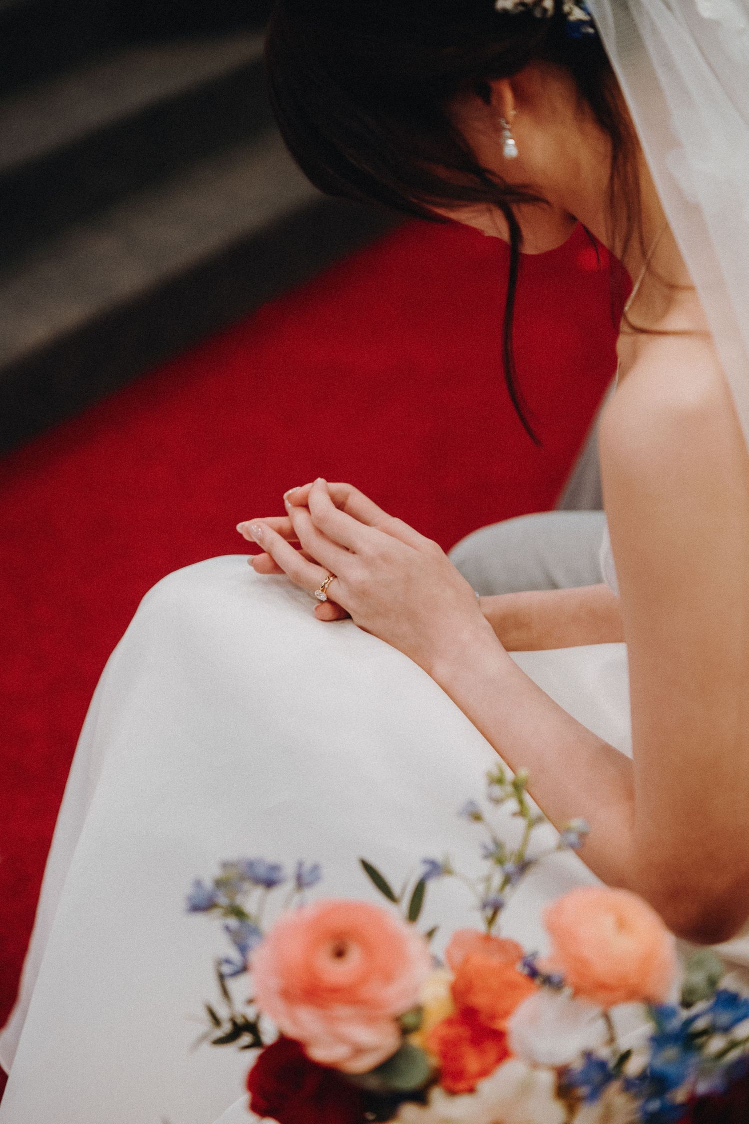 A close-up of a bride's hands with peach and blue flowers in the foreground.