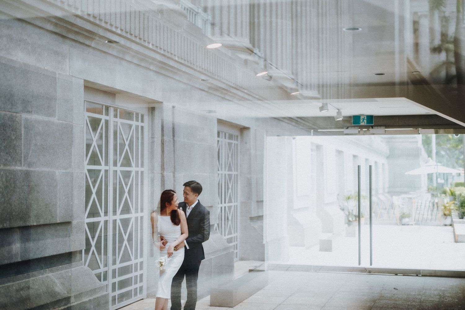 A romantic scene unfolds in a modern white hallway with geometric architectural details.