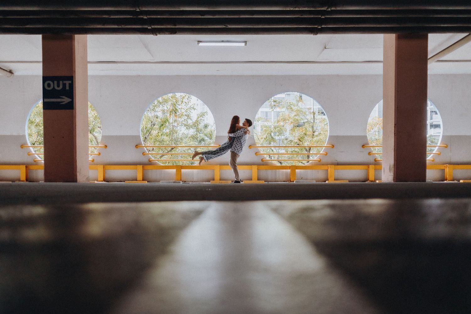 A silhouetted couple embraces in a parking structure with illuminated circular wall decorations.