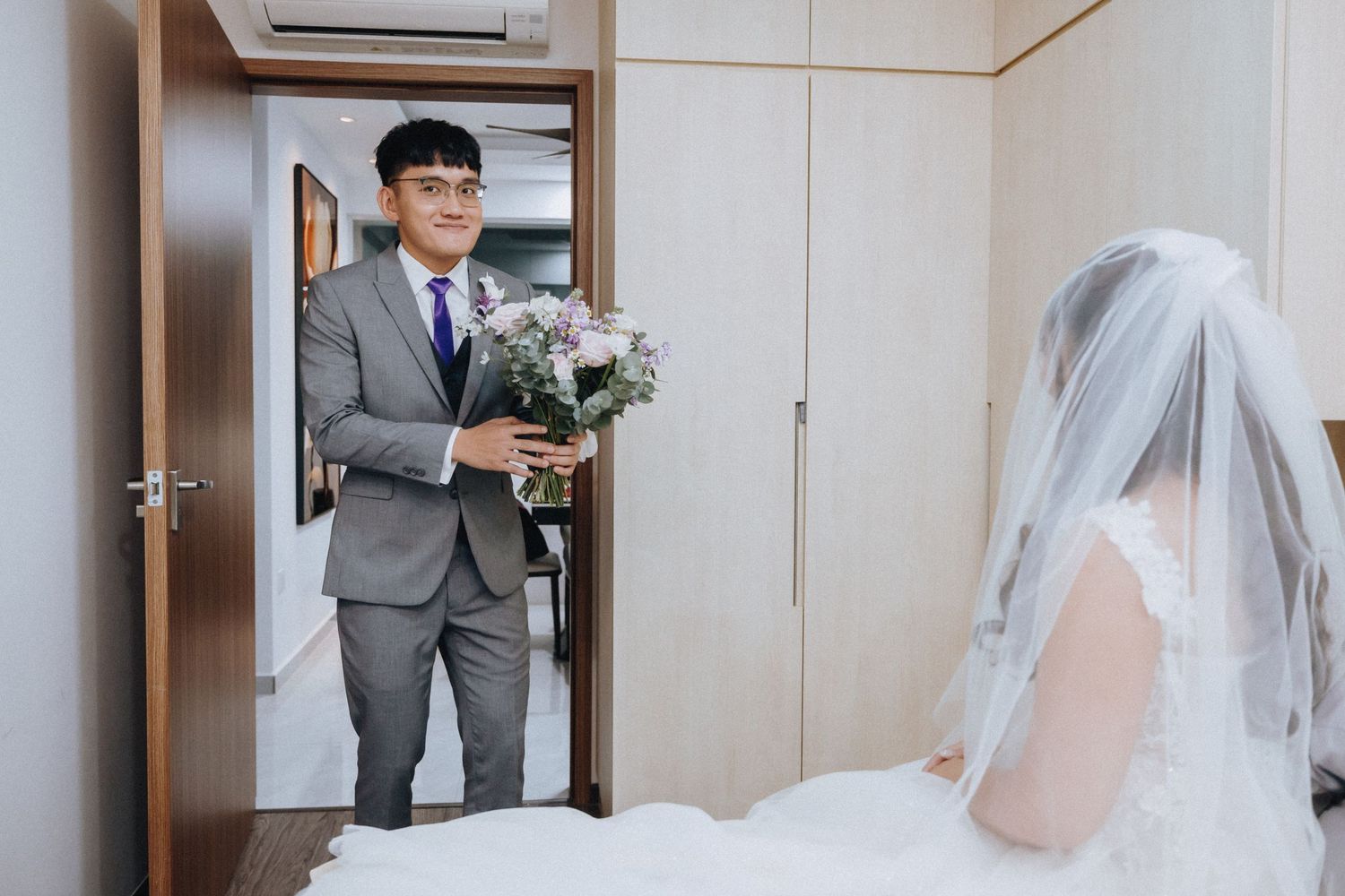 A wedding couple shares an intimate first look moment in a hallway with elegant decor.