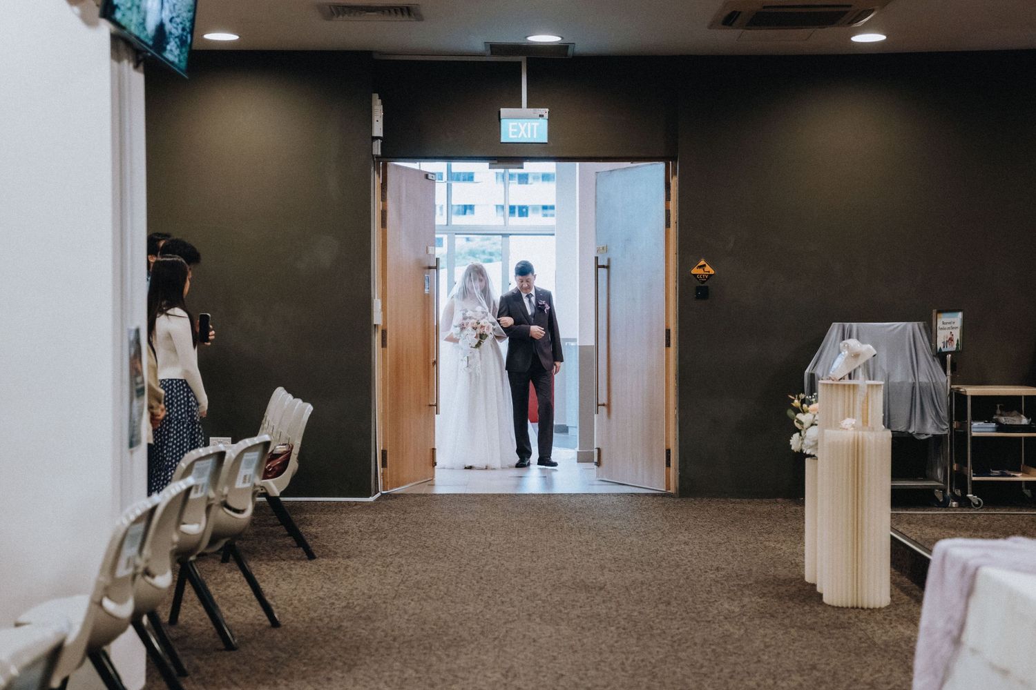Empty modern event space with recessed lighting and dark walls prepared for a ceremony.