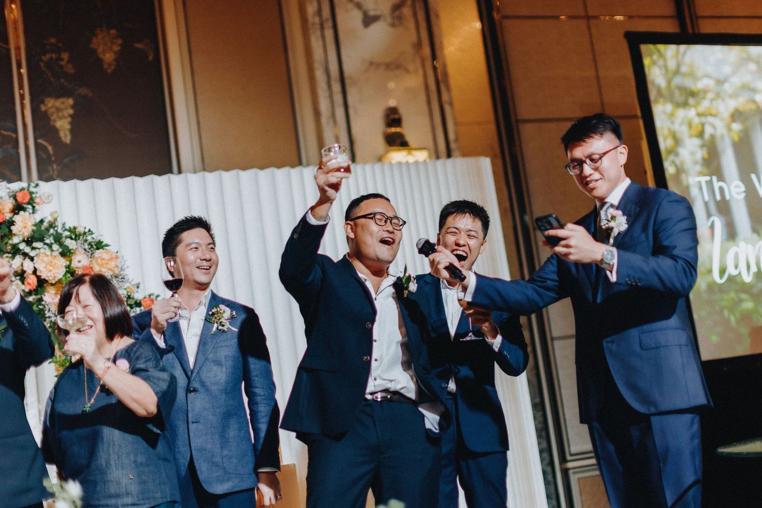 Groomsmen in dark suits performing synchronized dance moves at wedding celebration.