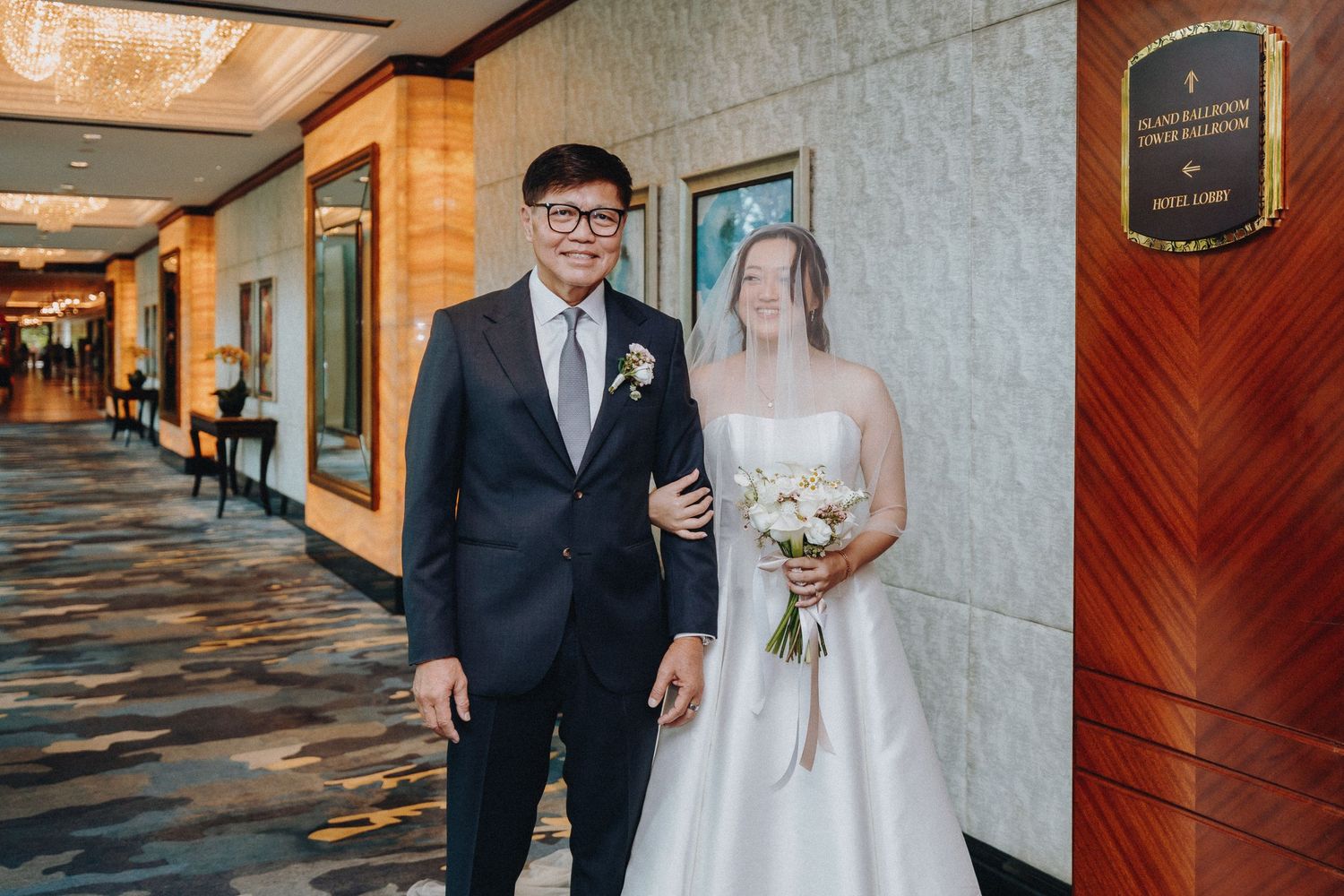 Newlyweds walking together through an elegant hotel hallway with patterned carpet.