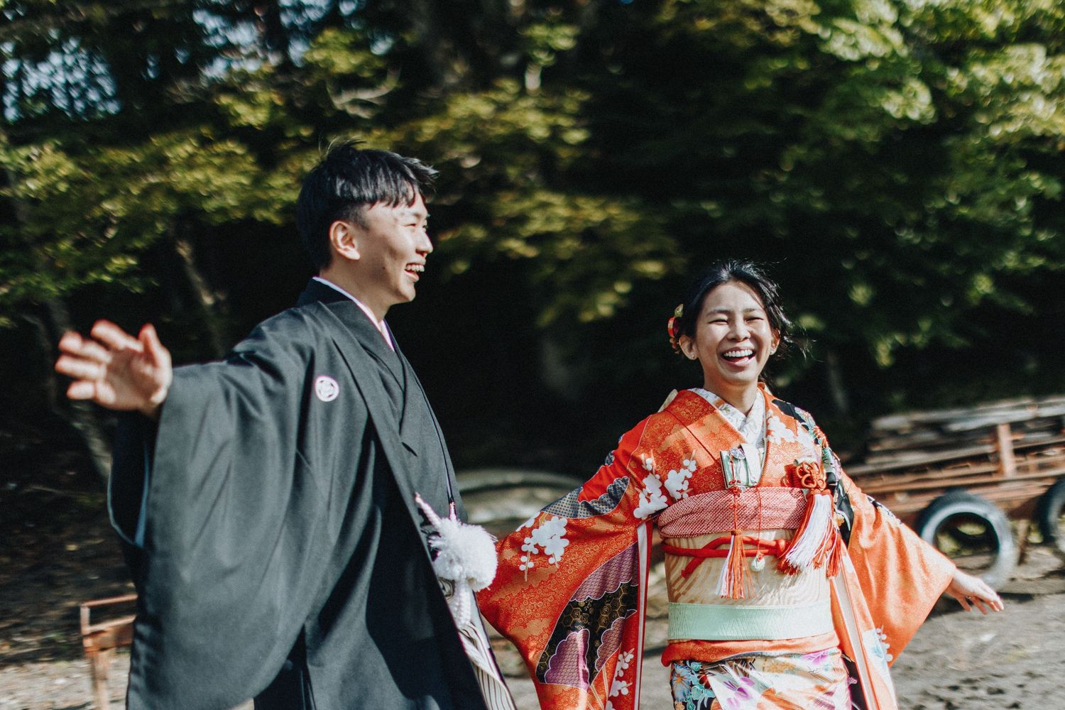 Traditional Japanese wedding couple shares a joyful moment among green trees.