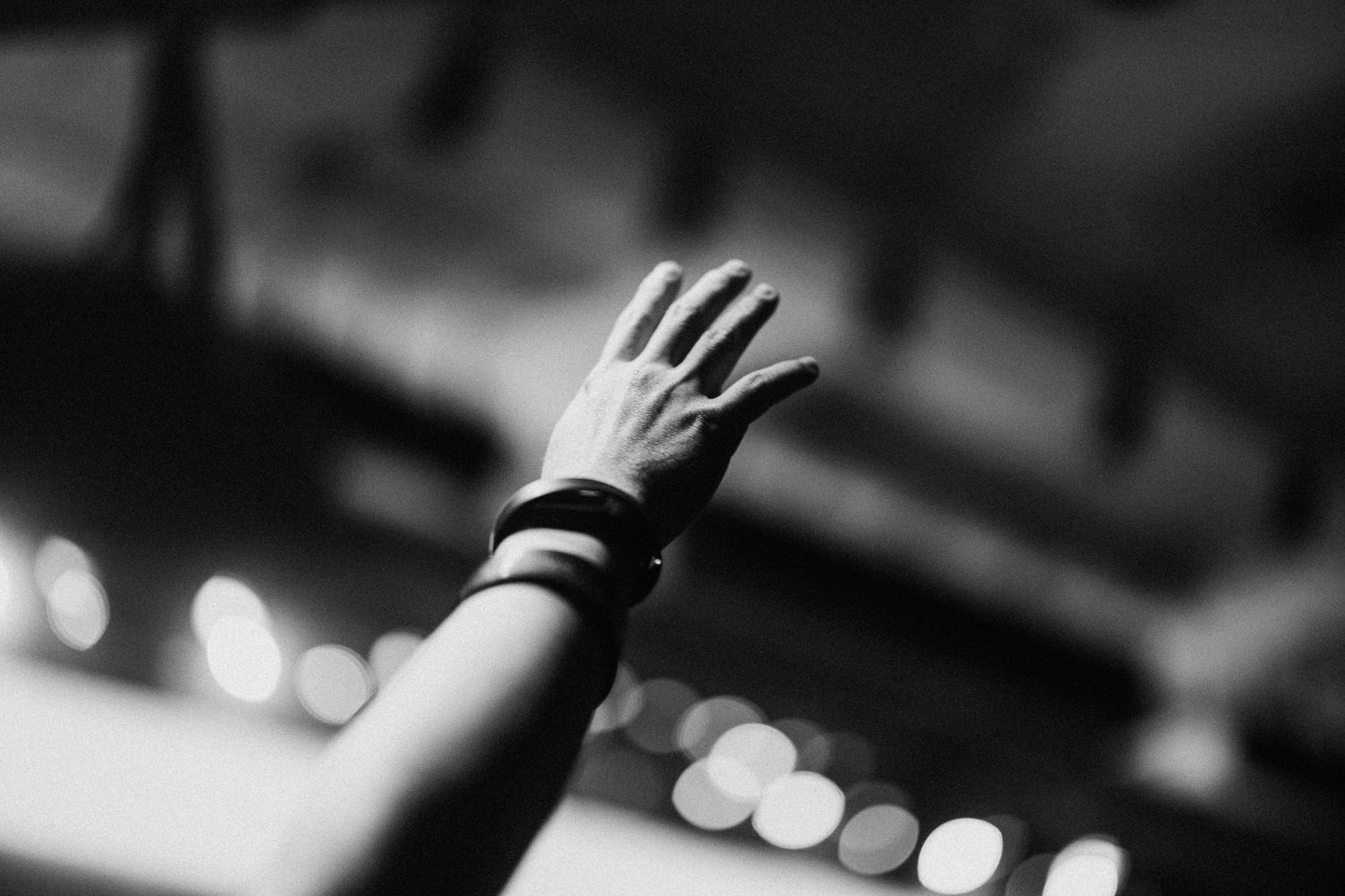 Silhouetted hands raised in worship against a dark background with soft spotlights.