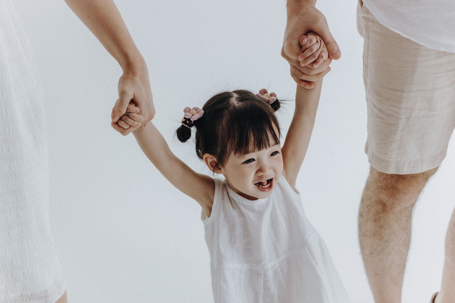 Joyful moment of child being lifted by hands against white backdrop.