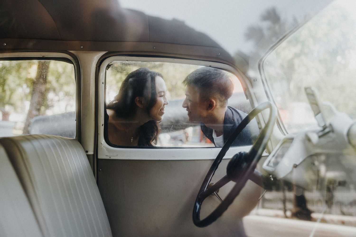 Interior view through vintage car windshield showing leather seats and classic dashboard.