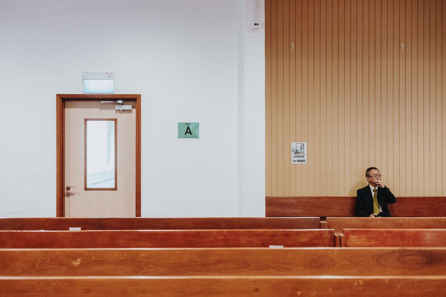 Wedding guests seated in wooden pews with warm lighting and minimalist church interior design.