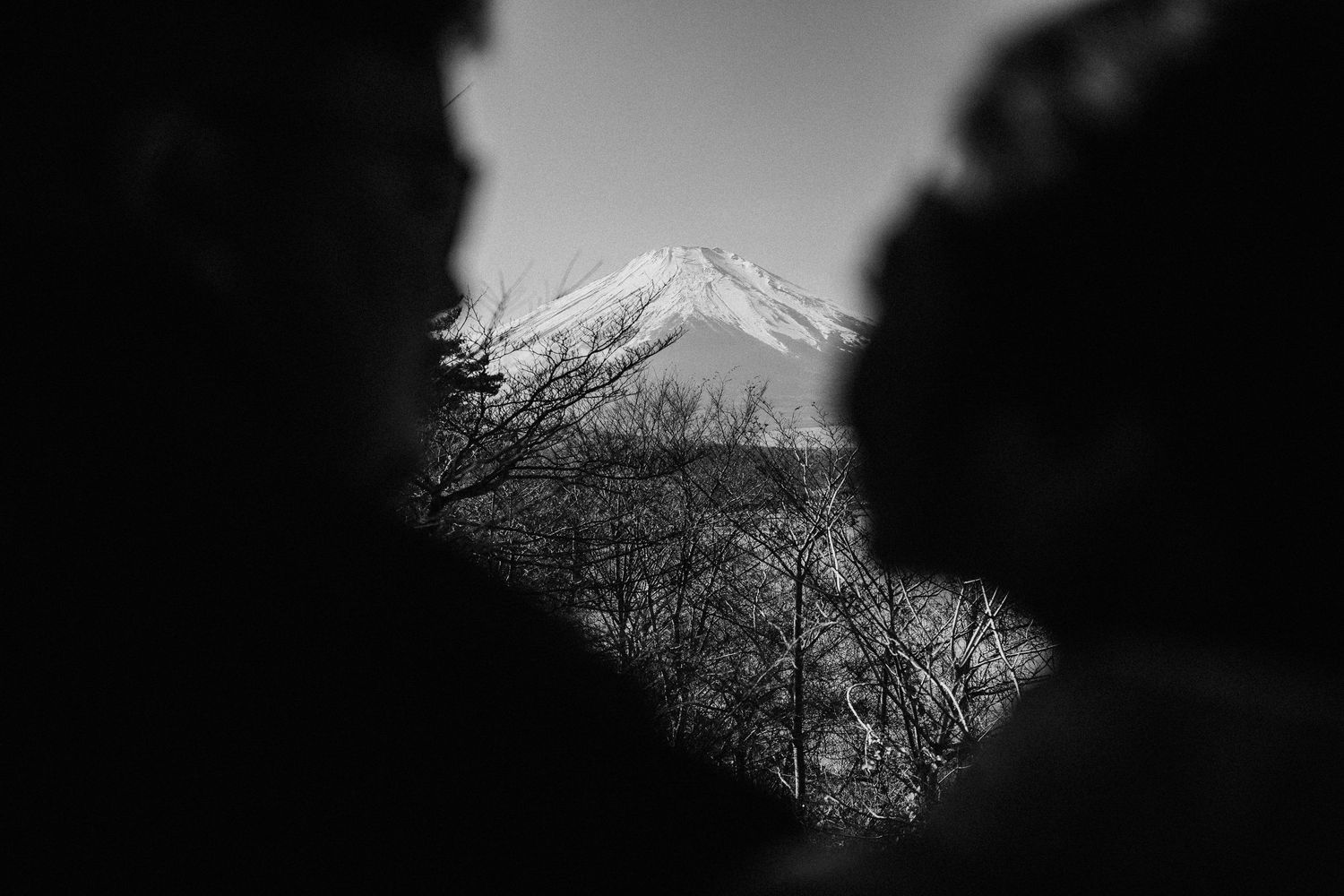 Black and white silhouette of Mount Fuji against a moody sky.