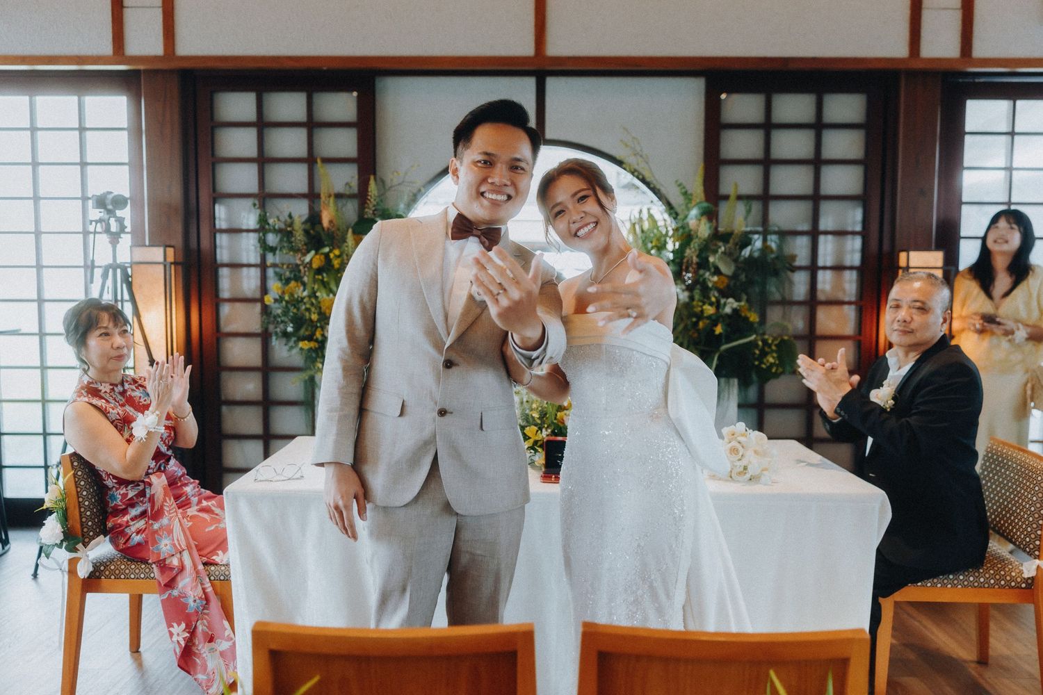 Wedding guests during a reception in a traditional Japanese venue with wooden interior details.