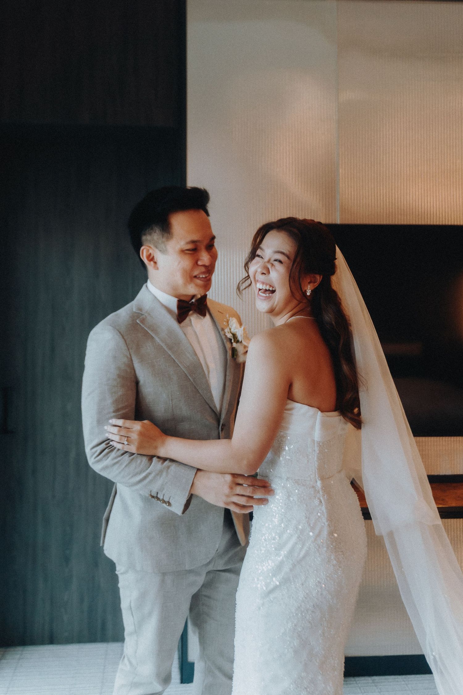 A tender moment captured between a bride in a white lace gown and groom in a light gray suit.
