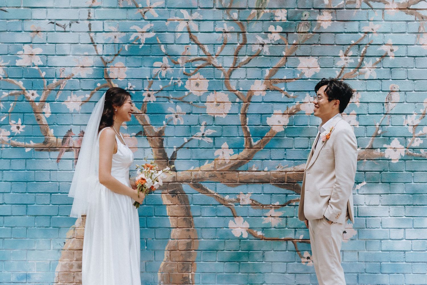 A romantic wedding photoshoot sequence against a turquoise brick wall with cherry blossoms in bloom.