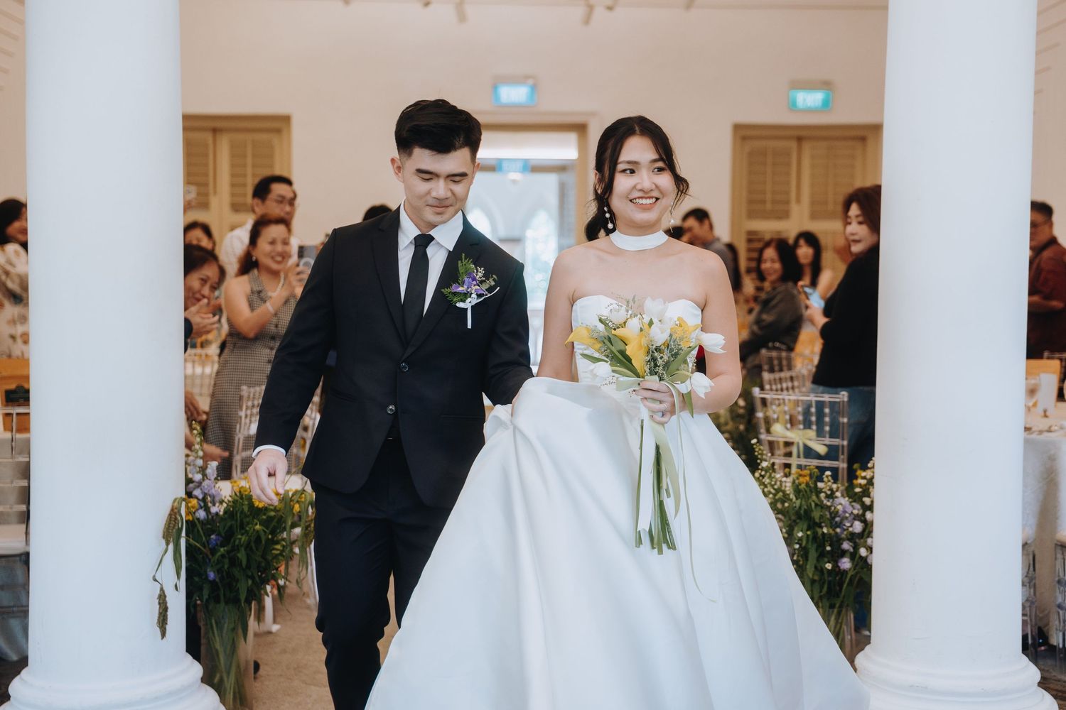 Smiling newlyweds walk down the aisle together after their wedding ceremony.