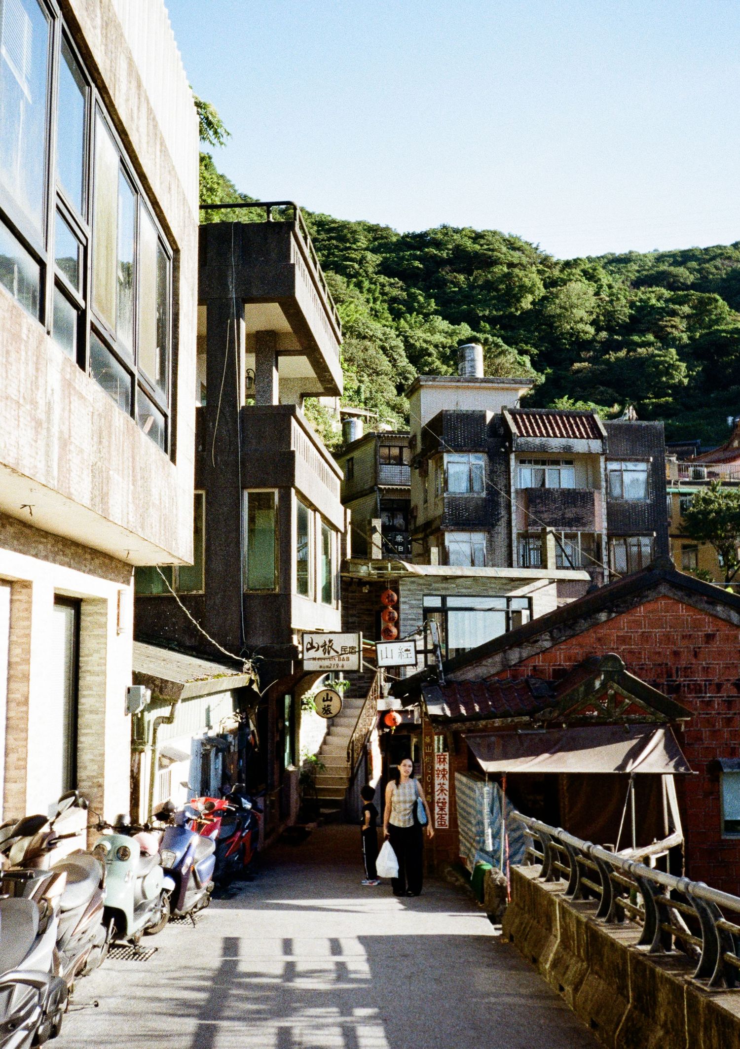 Japanese residential street on a hillside with white buildings and traditional architecture.