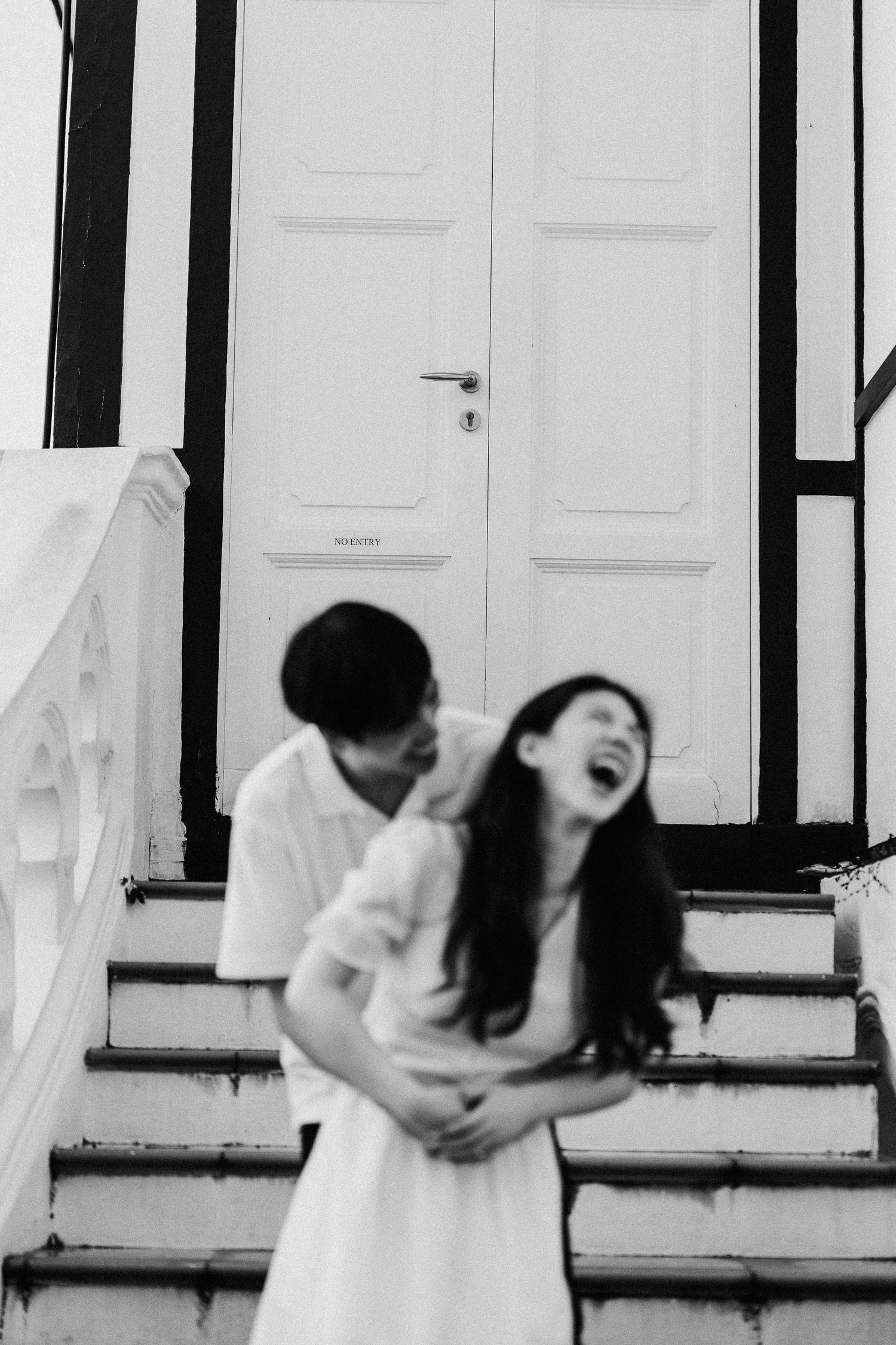 A joyful couple shares a candid moment on white outdoor stairs.
