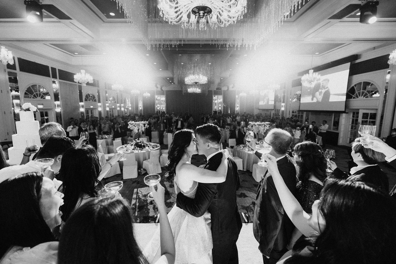 Black and white panoramic shot of a crowded wedding reception dance floor.