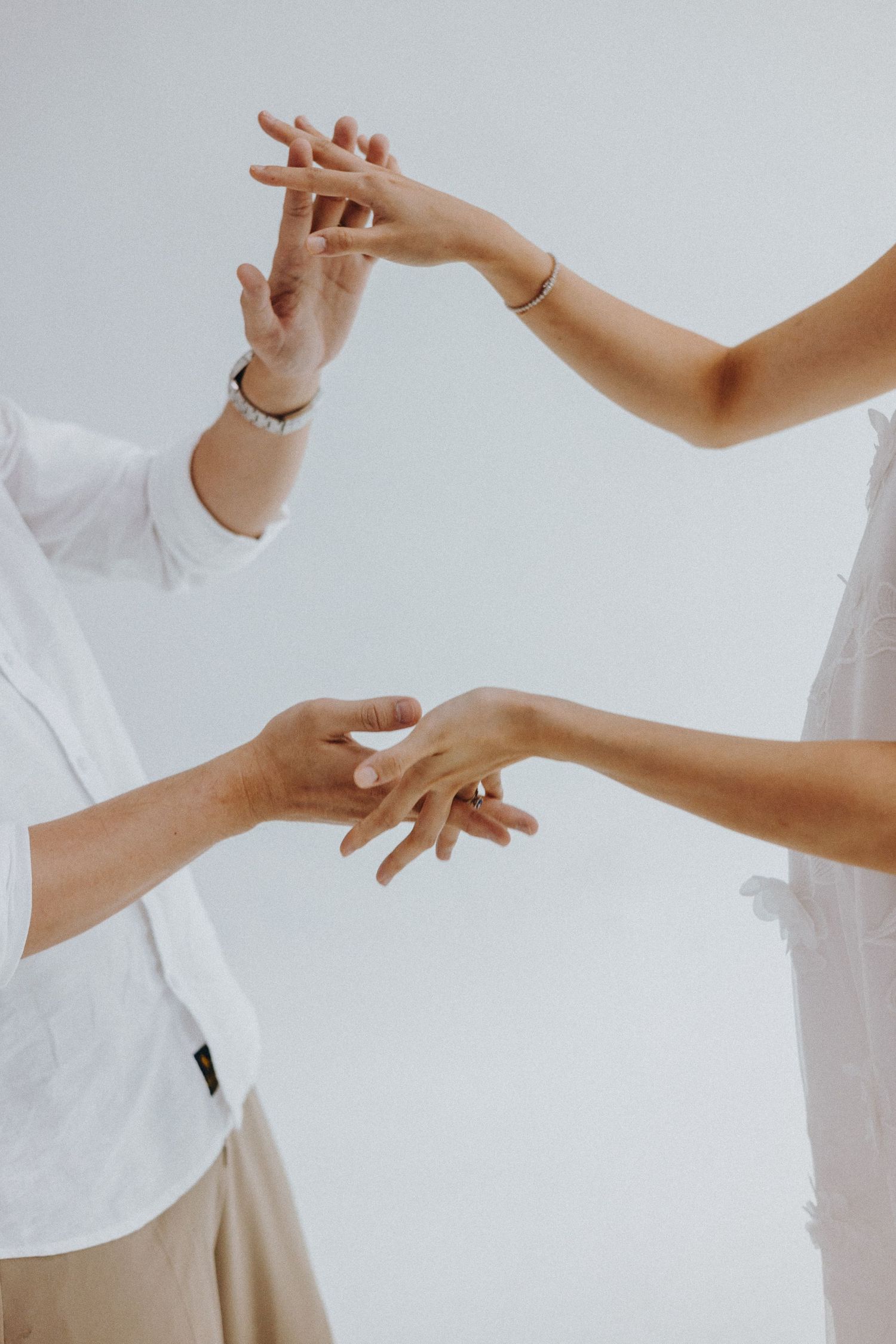 Two hands reaching and interacting in an artistic dance-like pose against a white backdrop.