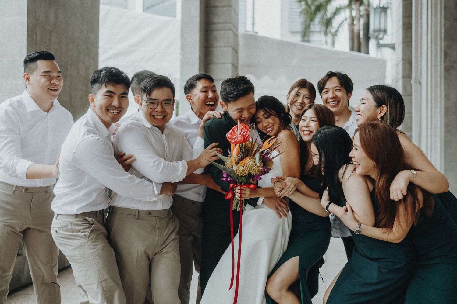Wedding party celebrating and posing together under covered walkway.