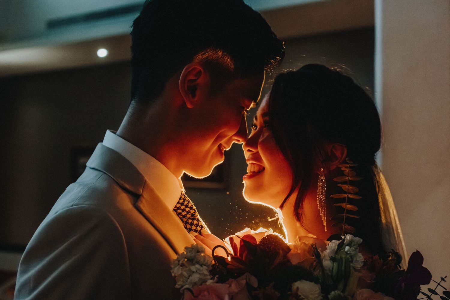 Dramatic silhouette of wedding couple in warm ambient lighting.