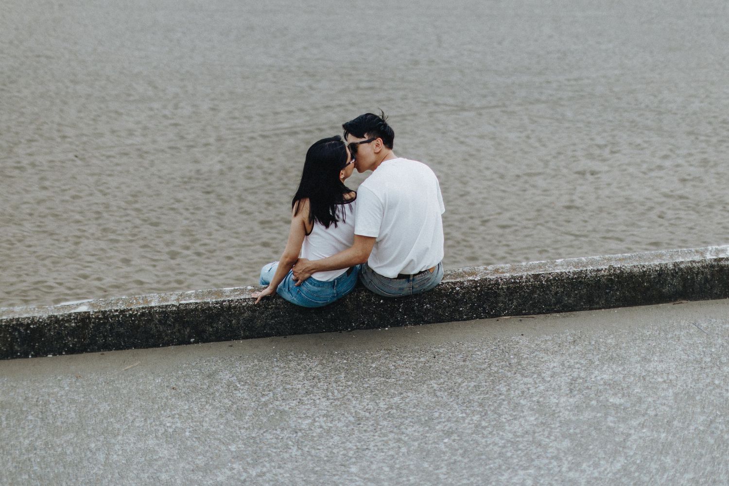 Couple sharing an intimate moment while sitting by the waterfront.
