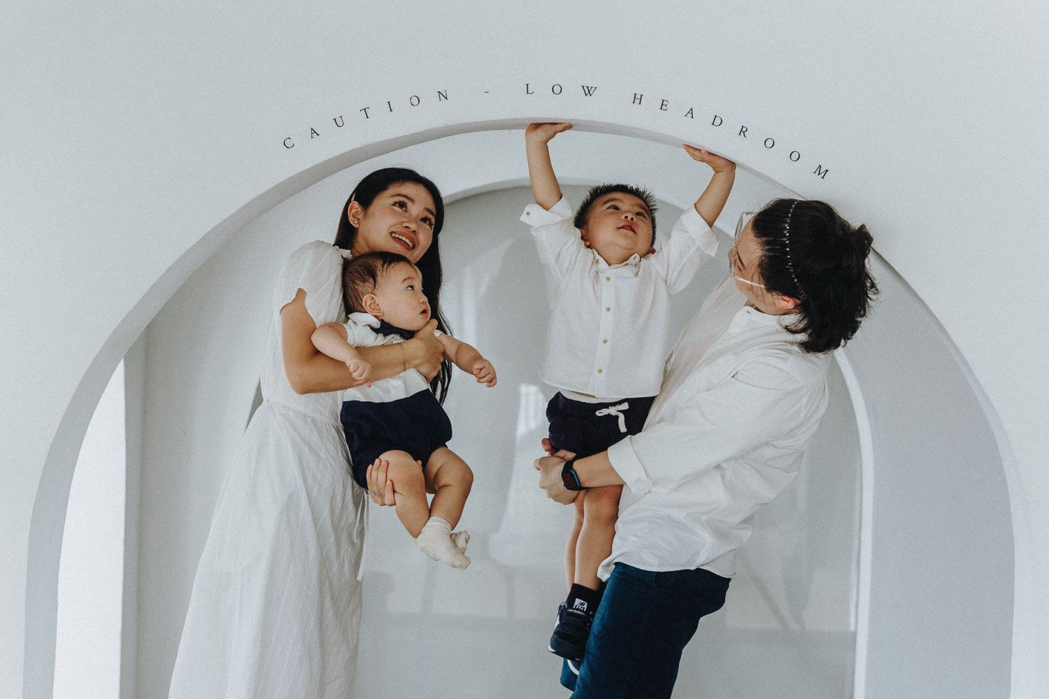Family plays and poses together under curved architectural archway in artistic photo composition.