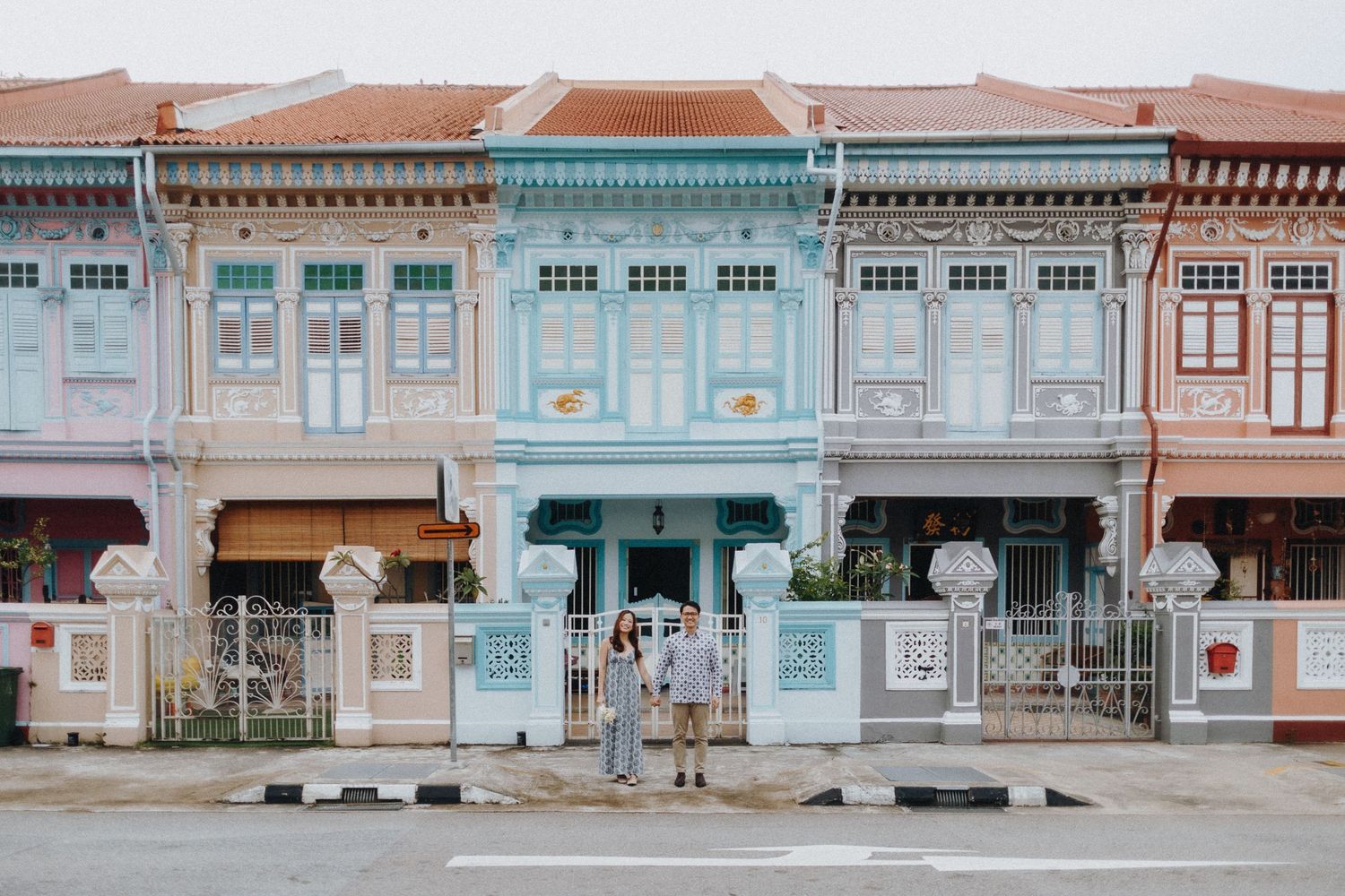 Colorful Peranakan shophouses with pastel blue and pink facades line a street in Singapore's heritage district.