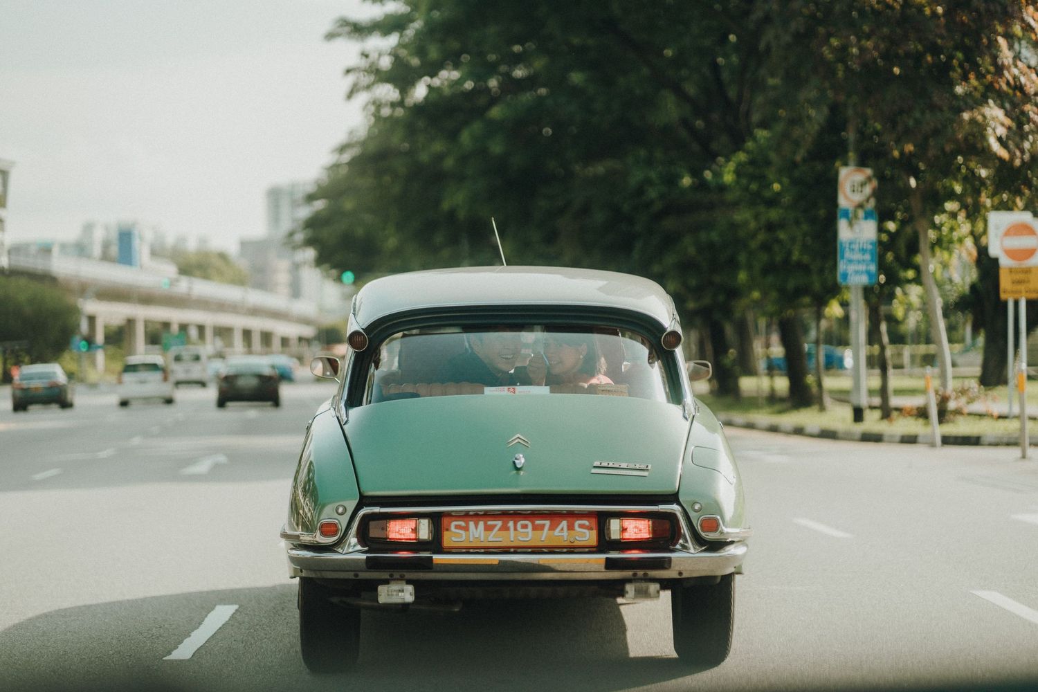 A vintage mint green Citroën DS photographed from behind on a city street.