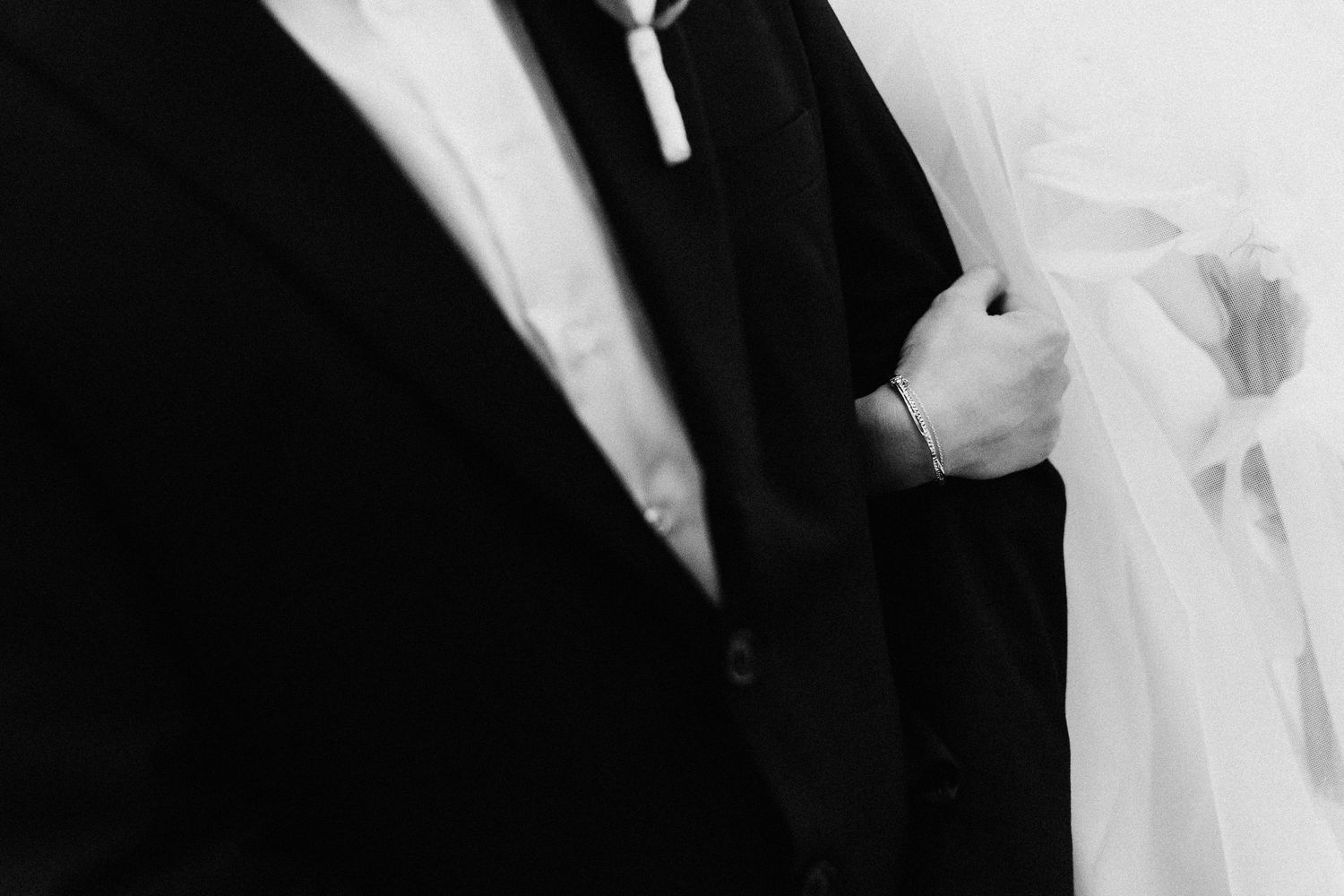 Close-up black and white image of hands exchanging wedding rings during a ceremony.