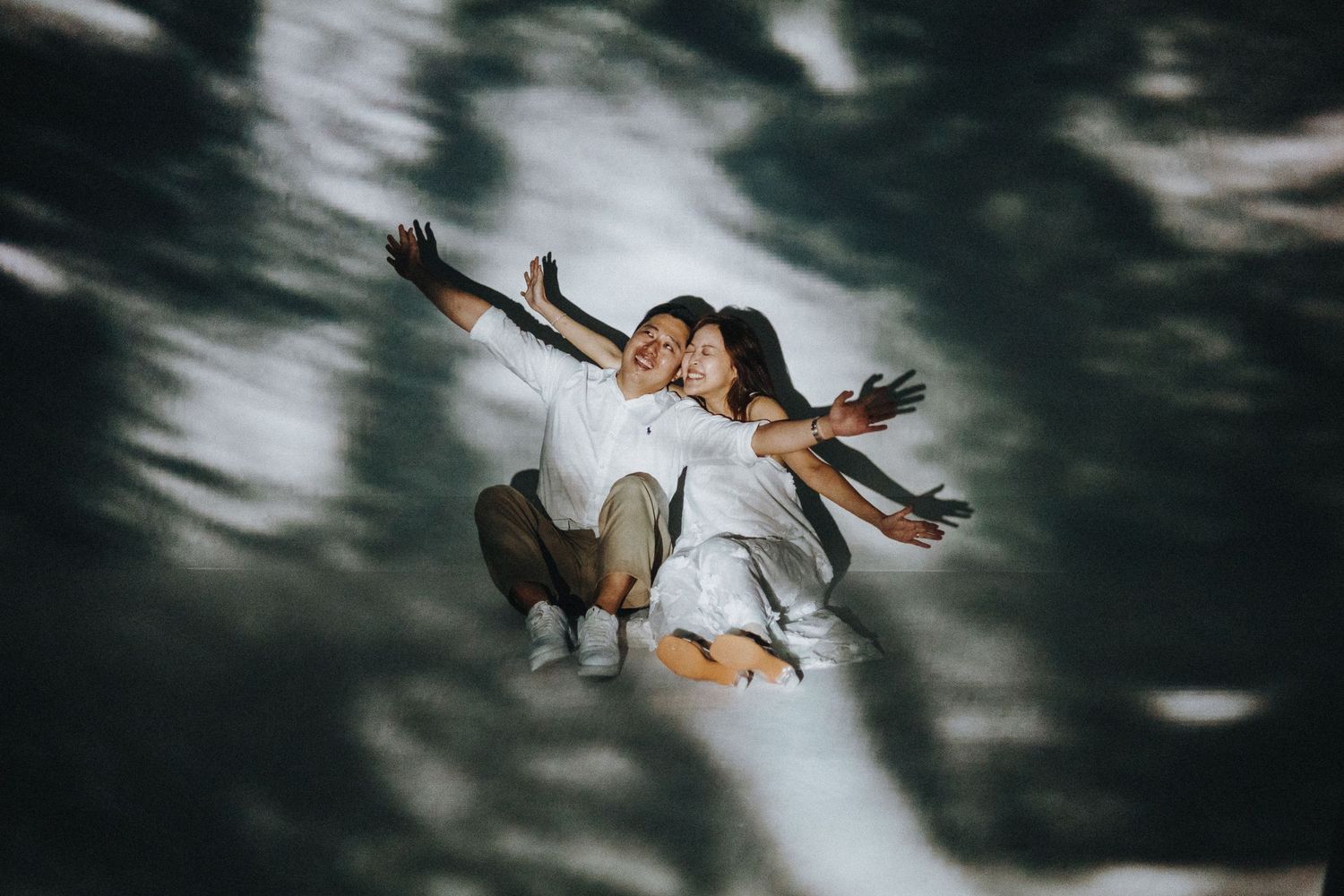 A creative couples photo with dramatic lighting shows them appearing to float together.