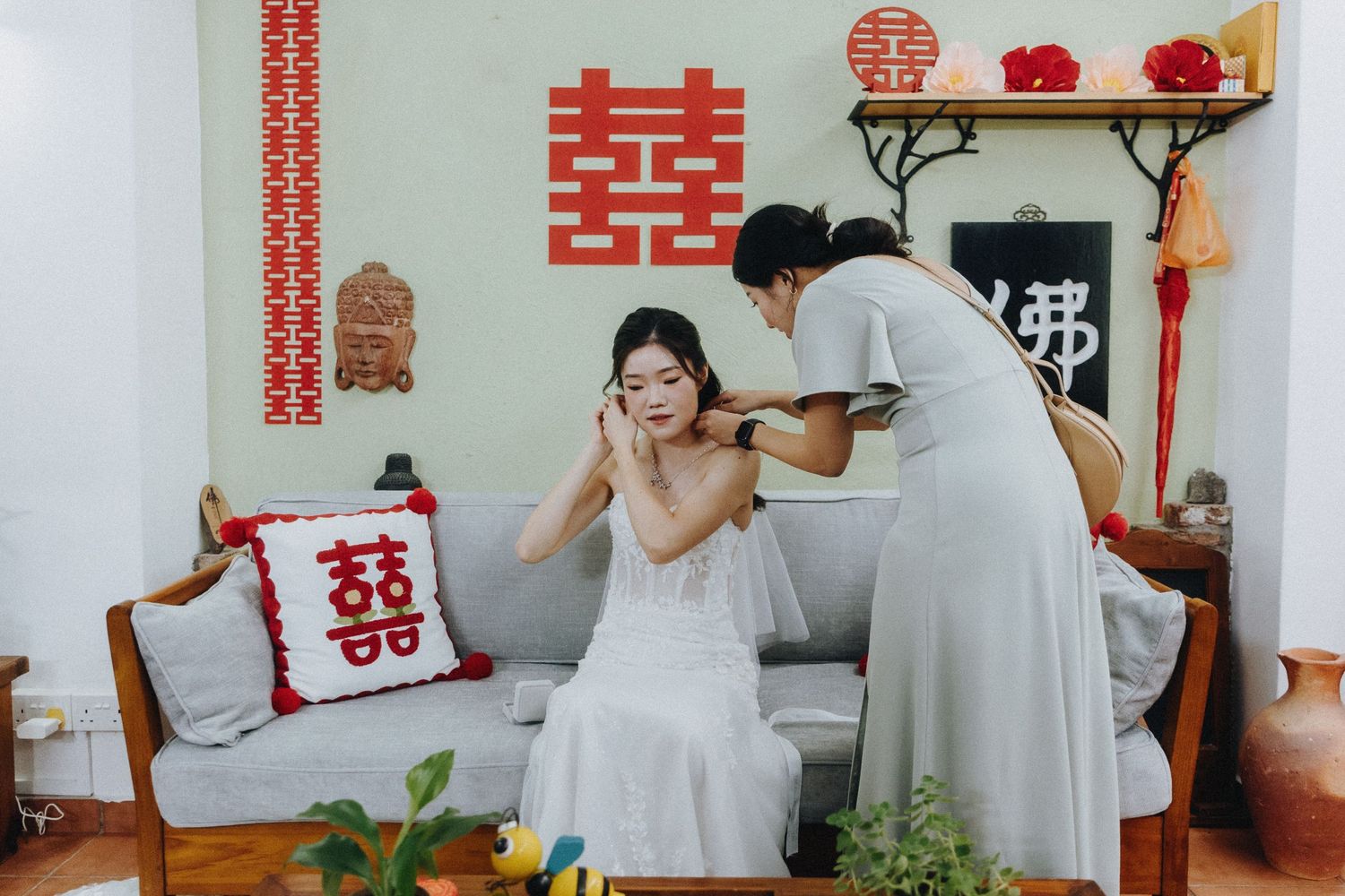 Traditional Chinese double happiness symbols and wedding decorations adorn a white wall for a tea ceremony celebration.