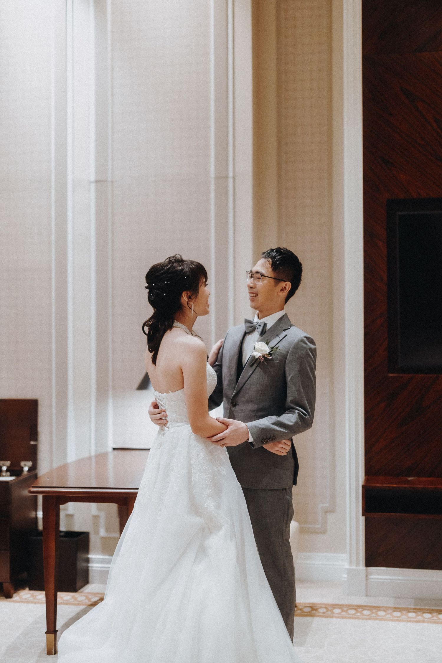 A couple shares an intimate moment in their wedding attire against a backdrop of white columns at an elegant venue.