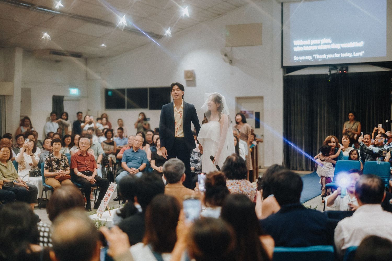 Large audience seated in an indoor venue during a presentation.
